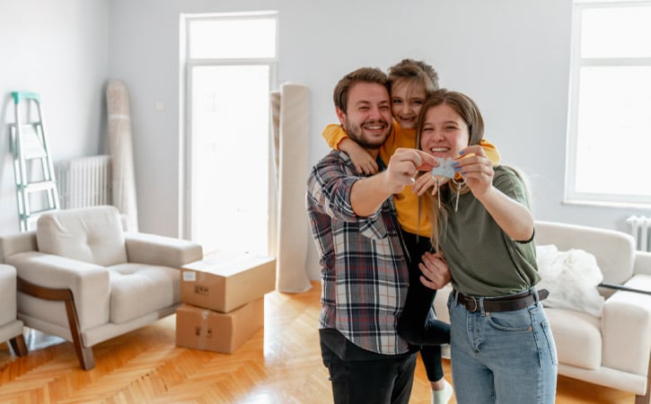 A family hugging and holding the keys to their new Asheville home