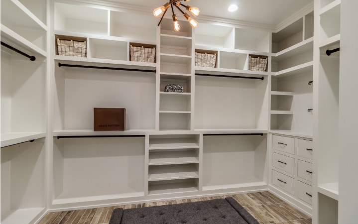 A custom-made closet, part of a full bedroom remodel. The closet is painted white with brown accents, and has plenty of cubbies for storage.