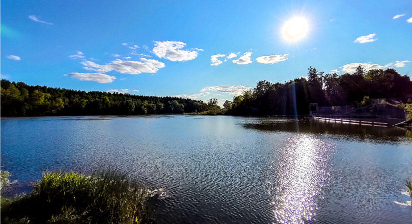 The sun hangs low in the sky above the Rouge River in Markham, Ontario, during an early summer evening.