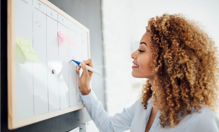 A woman creating a moving checklist on her whiteboard