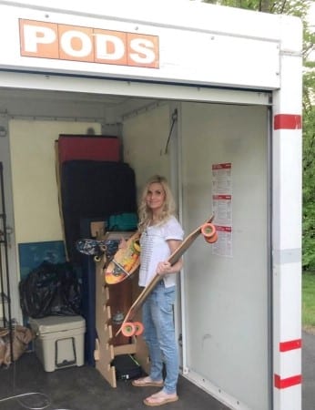 Michele from Hello Lovely is standing in a PODS portable container holding her son's skateboards as she helps to load it up. 