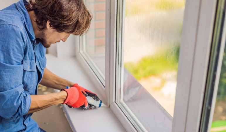 A man using sealant for his window