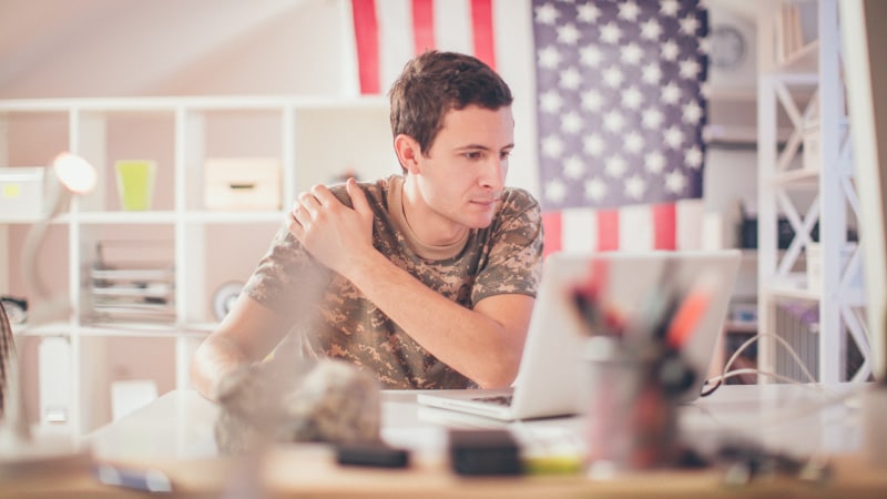 A military serviceman doing research online about military storage and moving services.