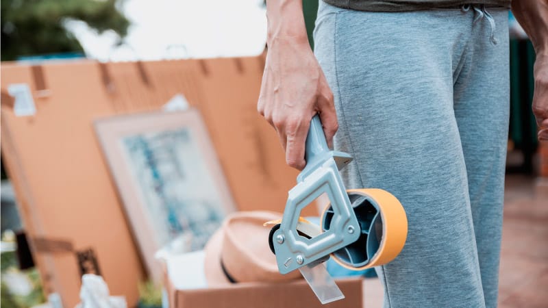 a woman holding a tape dispenser at a garage sale