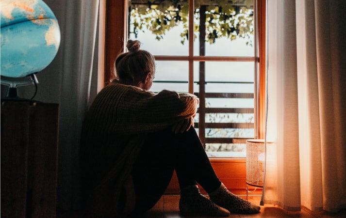 A woman with island fever sitting in her home and looking out the window