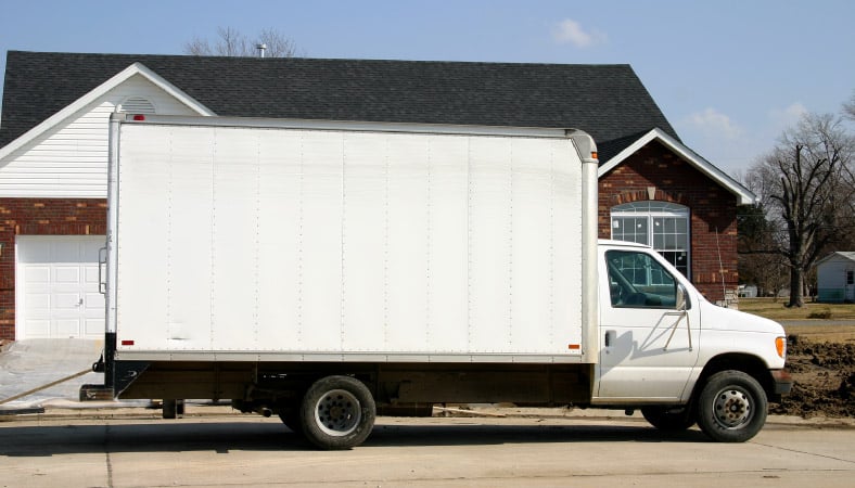 A white moving truck rental parked in front of a residential home. 