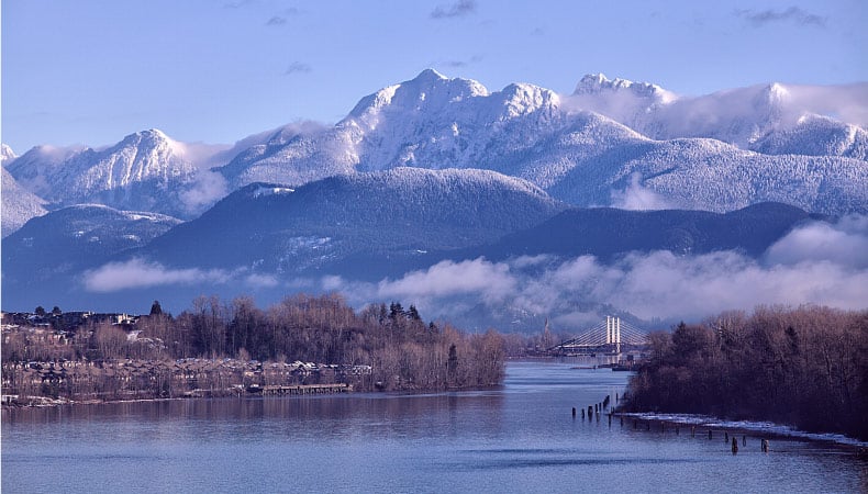 Fraser river in the morning seen from Surrey in winter, mountains heavily covered with snow. 
