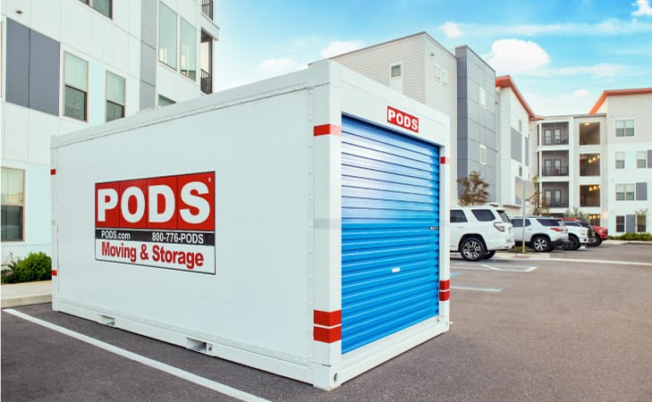 A PODS moving and storage container positioned in the parking lot of an apartment complex
