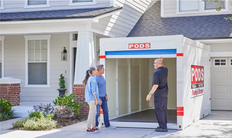 A couple standing in their driveway, checking out their PODS storage container with the PODS driver