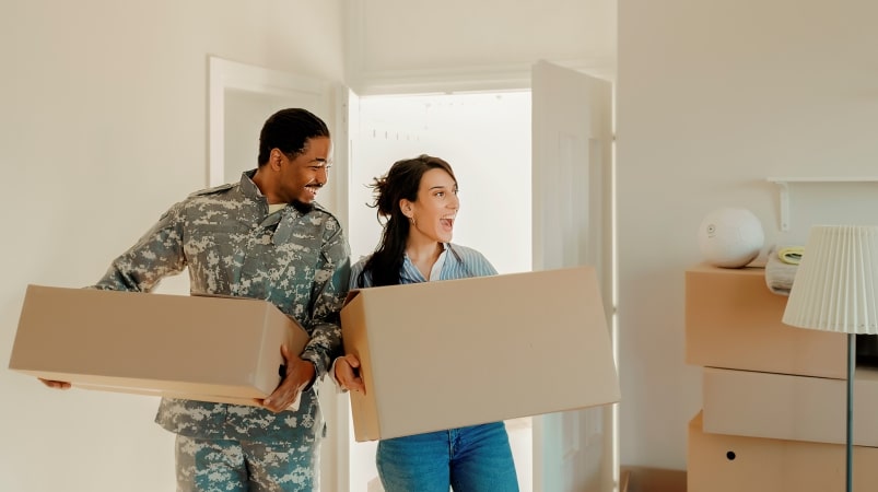 An American serviceman and his wife are carrying moving boxes into their new home in Oahu, where they've recently relocated for a PCS move.