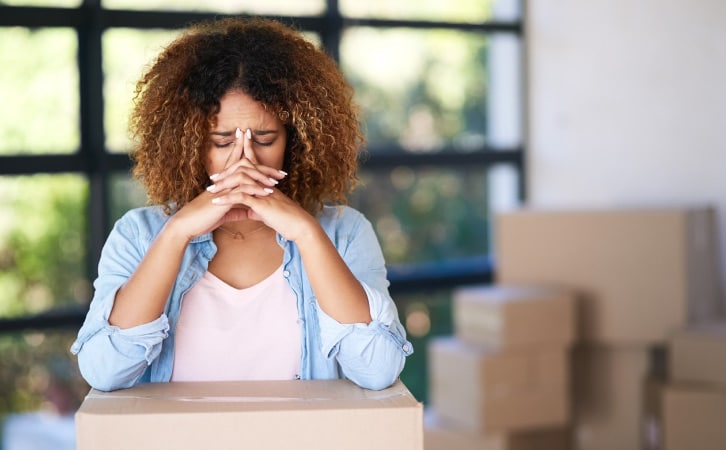 A frustrated woman leaning on a moving box
