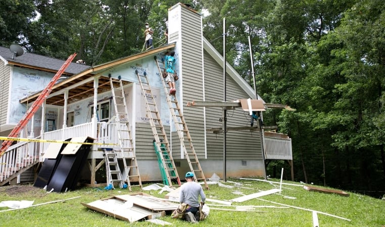 Three men are working on renovations of a two-story home for a U.S. veteran.