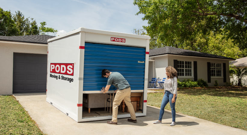 A couple opening their PODS moving and storage container in their driveway