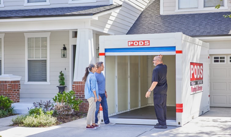 A PODS driver shows a couple the inside of their PODS moving container which is located in their driveway.