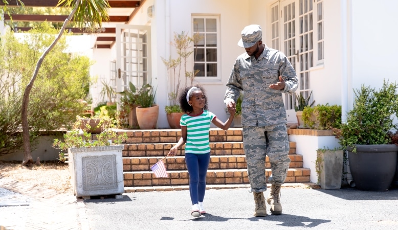 An American serviceman is holding his daughter's hand as he walks with her down the path in front of their new home on Oahu. 