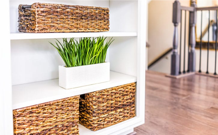 Matching wicker storage bins for organization, neatly arranged on shelves with a decorative plant