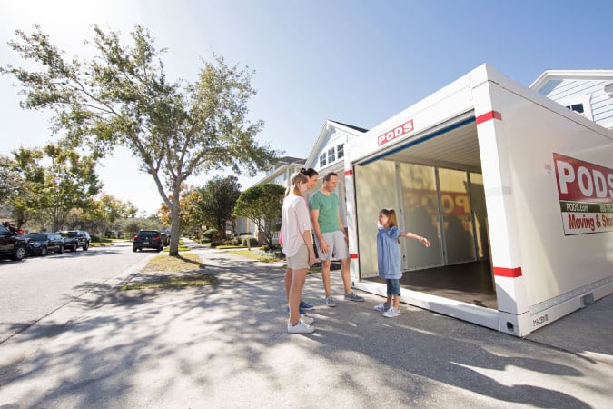 A family surrounding an empty PODS container