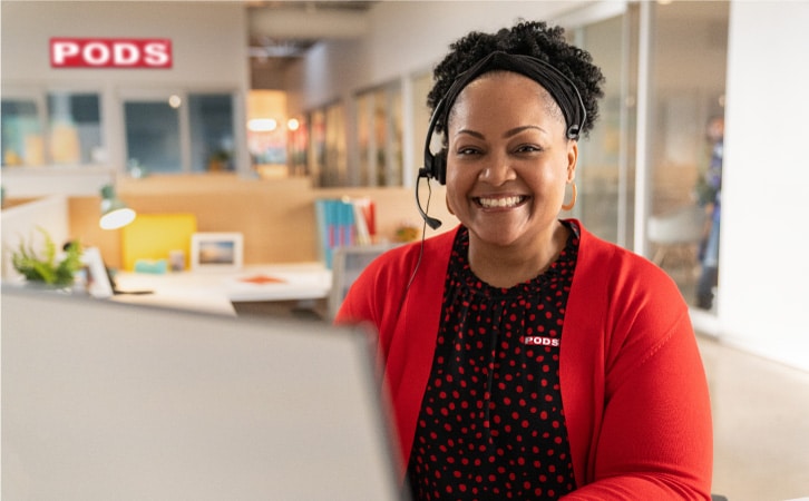 A PODS customer service rep smiling while helping a customer on the phone