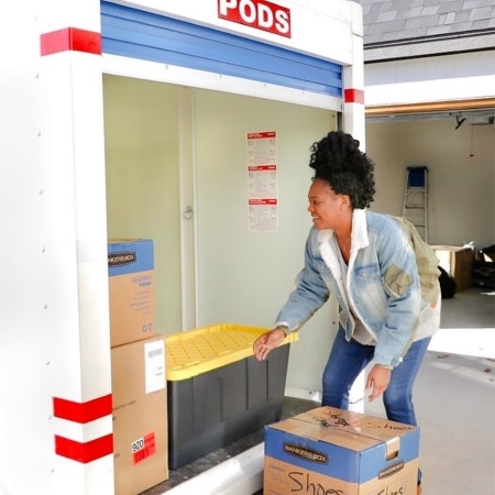 A woman is happily taking her time packing her PODS container. She’s already loaded some things, but there’s still plenty of room left for the rest of her belongings.