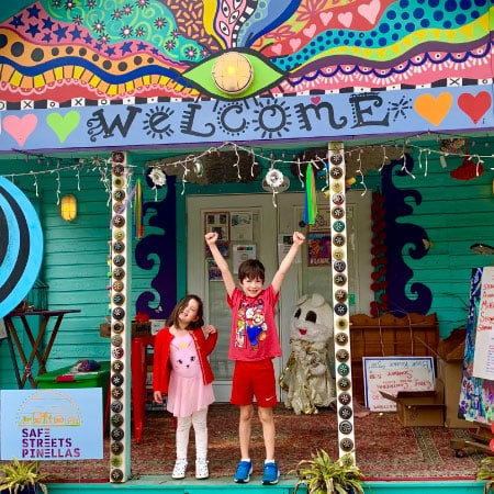 two happy kids in front of a colorful house