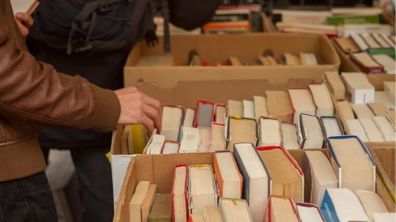 people browsing through boxes of used books at a garage sale