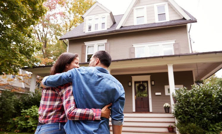 A happy couple in front of their fixer-upper home