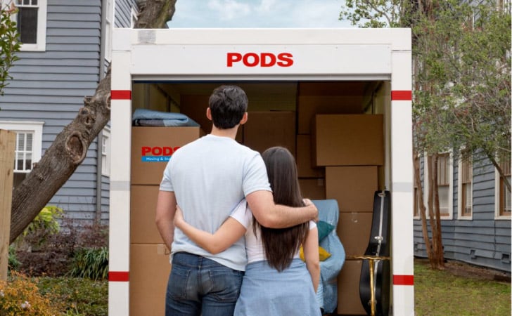 A couple standing in front of their loaded PODS container