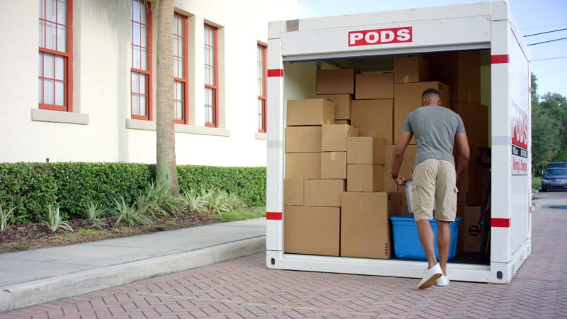 A military serviceman, in civilian clothes, is unloading his belongings from a PODS portable storage container.