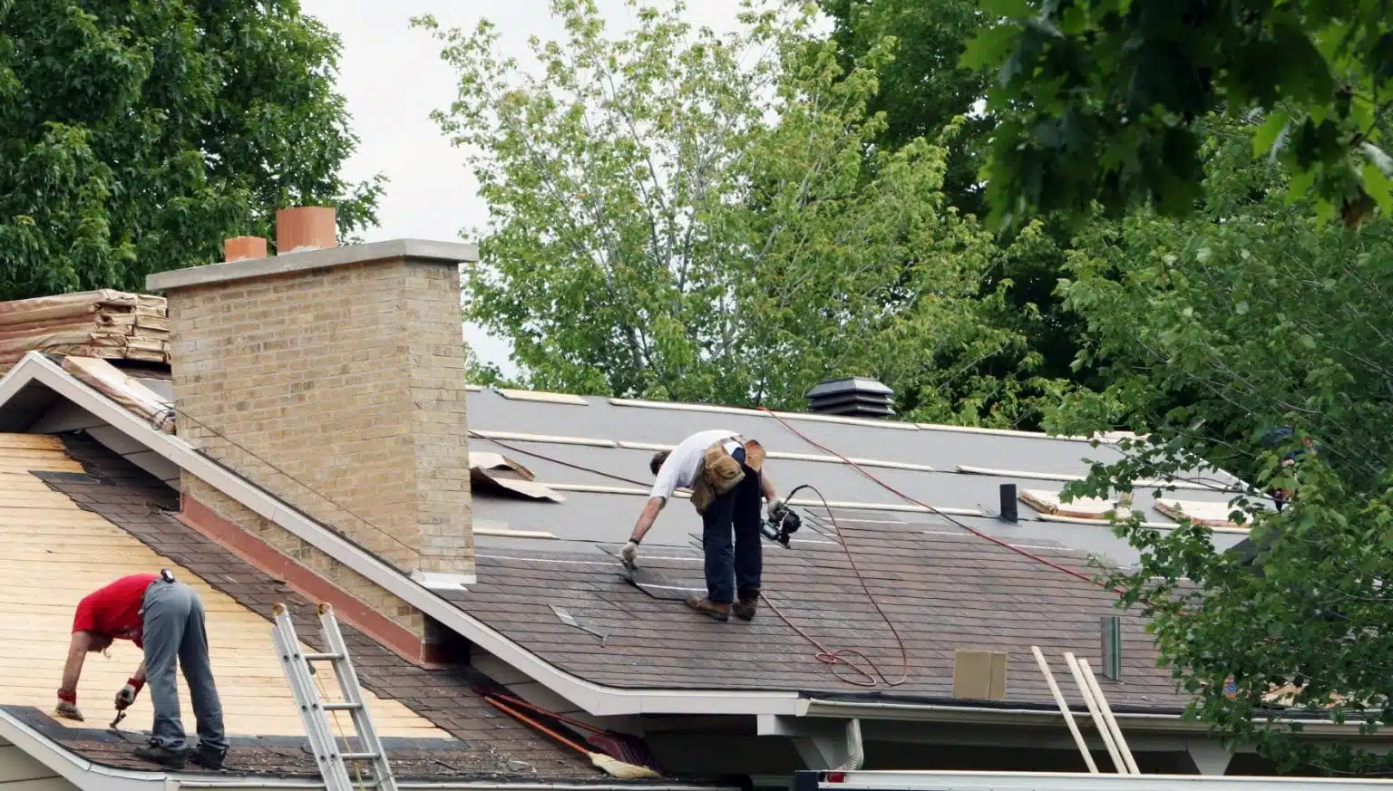 roofers laying new shingles on house
