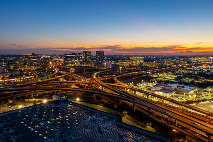 Aerial view of Frisco, Texas, at sunset. The city and its freeways are illuminated by street lights and office buildings. 