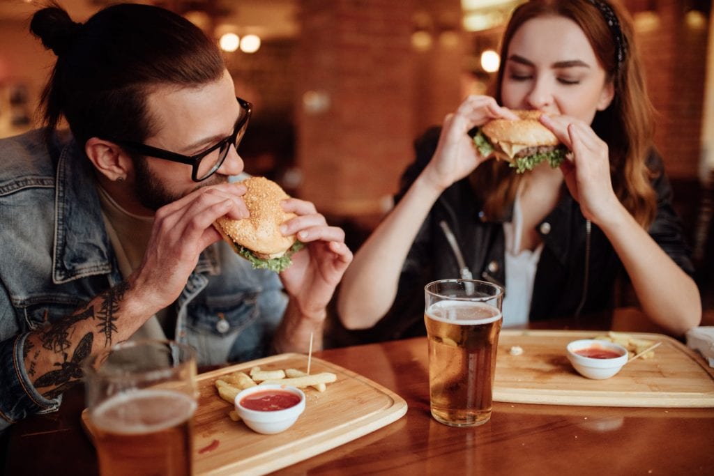 A couple is chowing down on hamburgers and draft beers at a local restaurant in their new city after completing a cross-country move