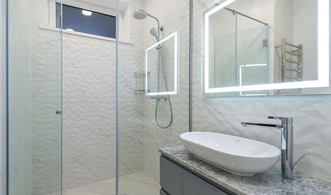 A walk-in shower with a back wall textured with a triangular pattern, bringing interest to an otherwise plain backdrop