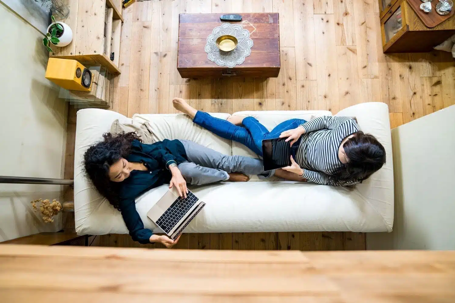 Overhead view of two roommates sitting on a couch together in their shared living space.