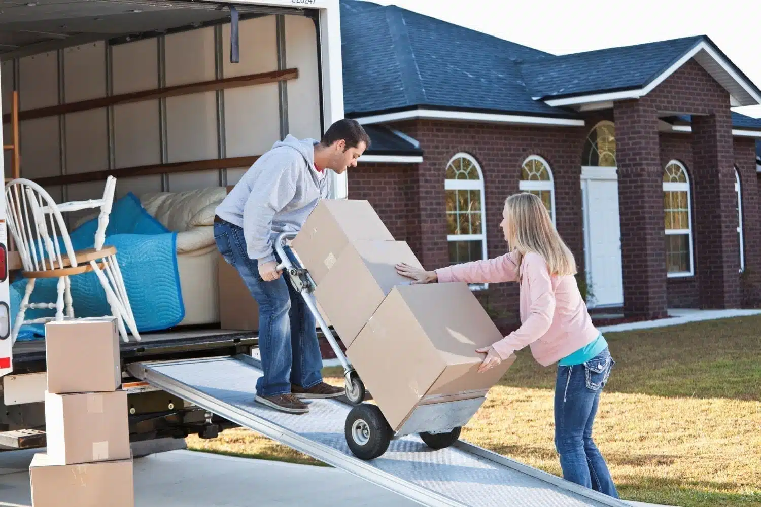 man and woman using dolly to load moving truck