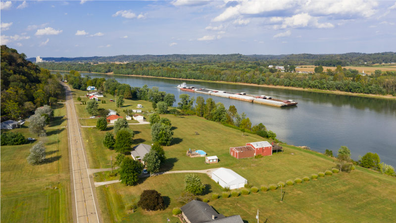 A river tugboat is pushing a line of barges along the Ohio River, past waterfront homes in Gallipolis, OH. 