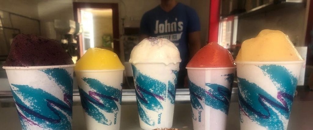 A variety of Water Ice flavors in paper cups lined up on a table at John's Water Ice in Philadelphia.