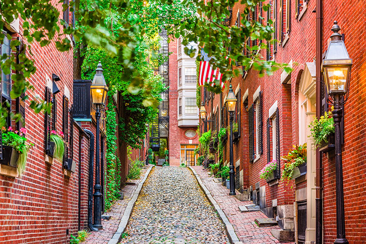 A cobblestone road lined by red brick buildings, echoing Colonial American architecture.