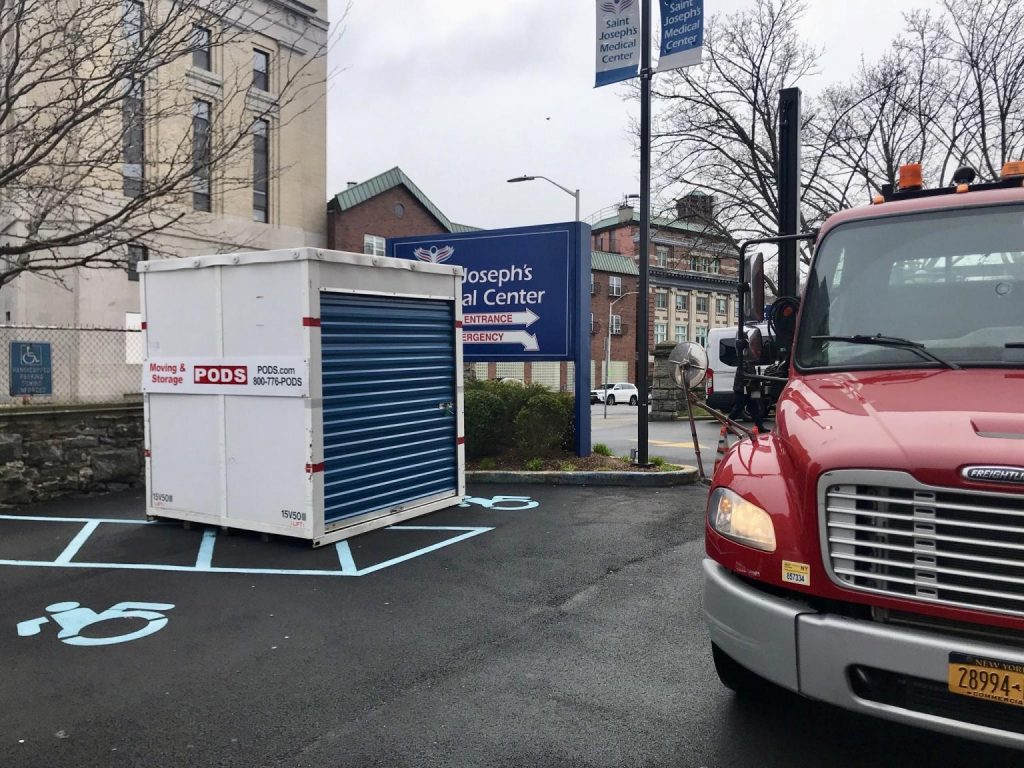 A PODS container being placed in a hospital parking lot space