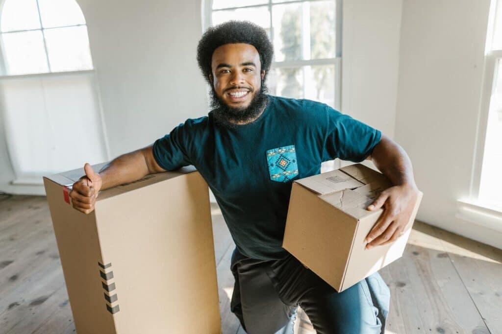 Commercial moving company employee holding boxes in empty room
