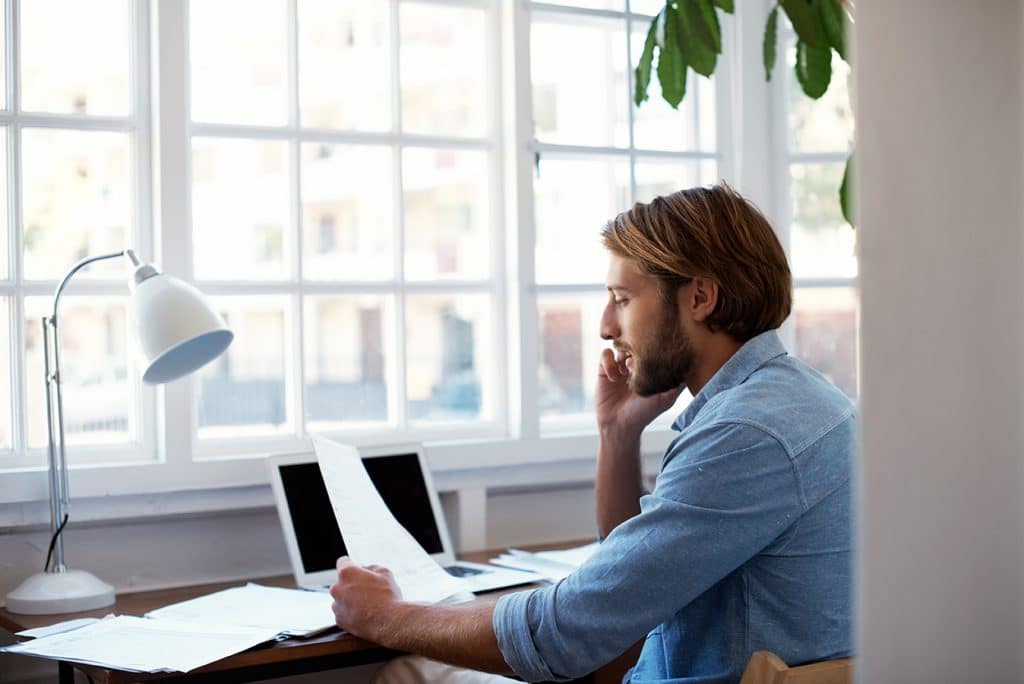 A man sitting at a desk and making a phone call