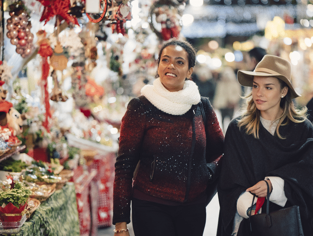 Two female holiday shoppers explore holiday market