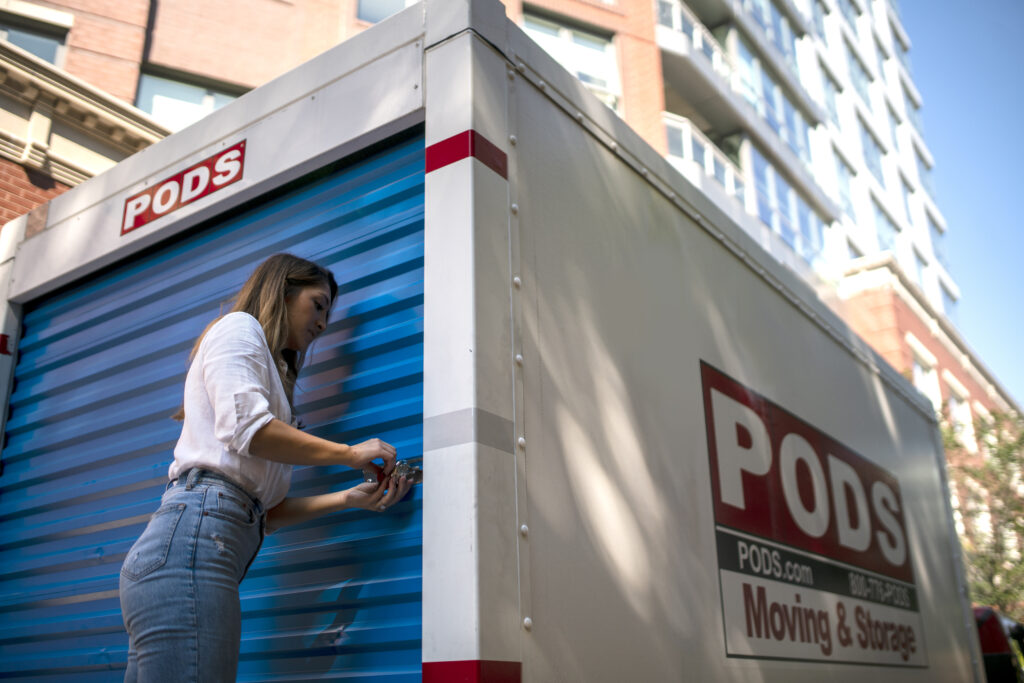 Young adult woman potentially moving to Austin, Texas locking a PODS container on a city street