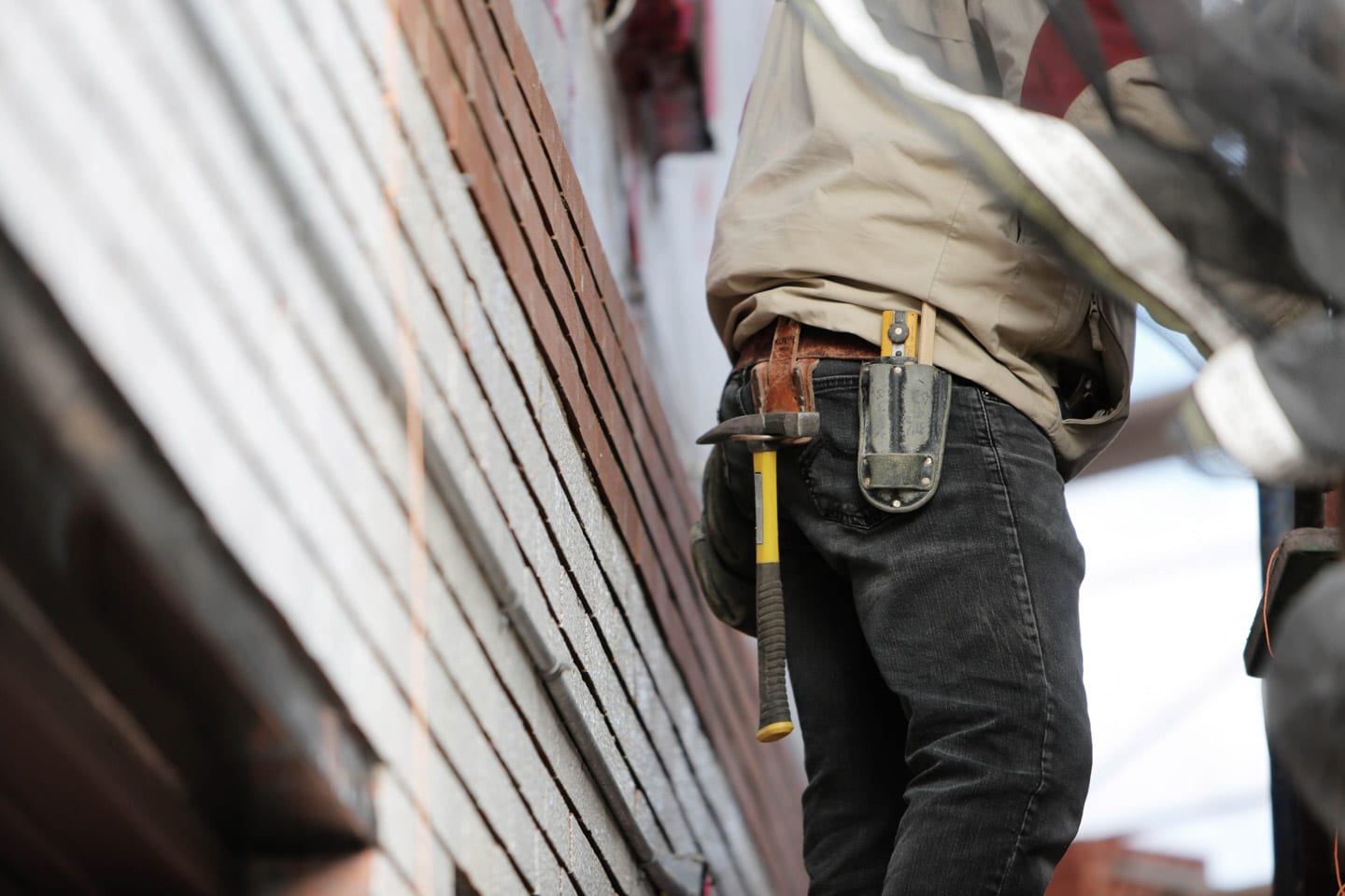 Worker on a jobsite with tool belt to prevent construction site injuries