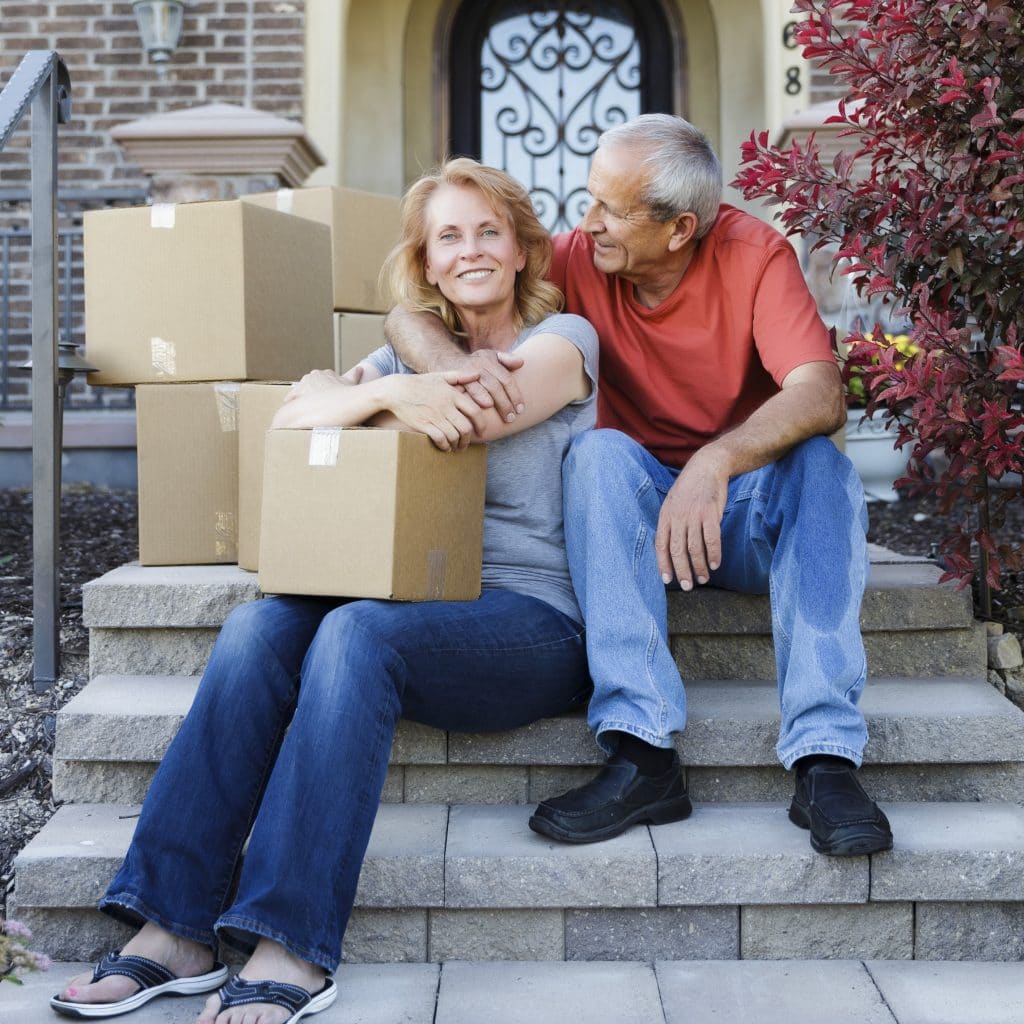 A relocating couple sitting on the steps of their home