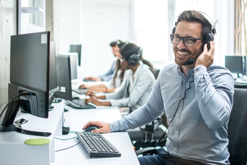 Call center employee smiling while providing a customer service experience over the phone