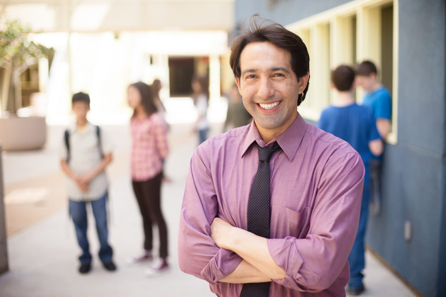 A male teacher standing outside classrooms on highschool campus