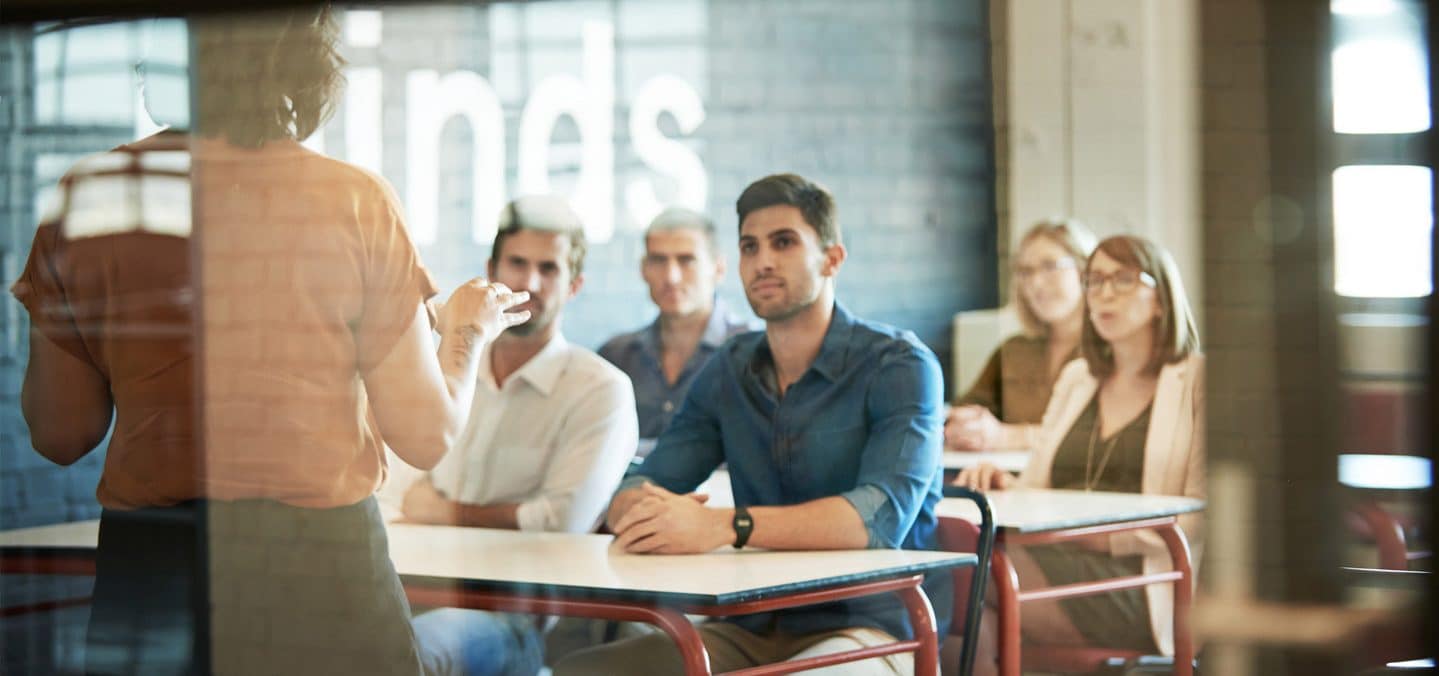 Students sitting at their desks and learning from a teacher in classroom