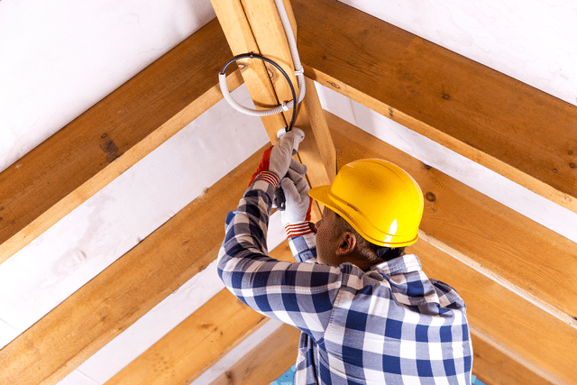 Electrician installing holiday lights on roof