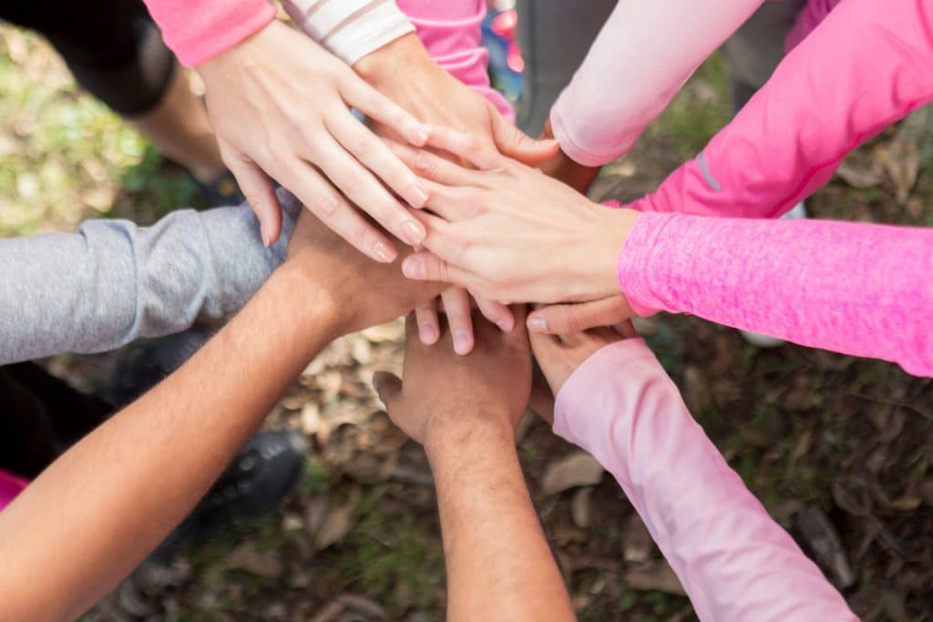 Charity walker participants placing their hands on top of one another in a huddle