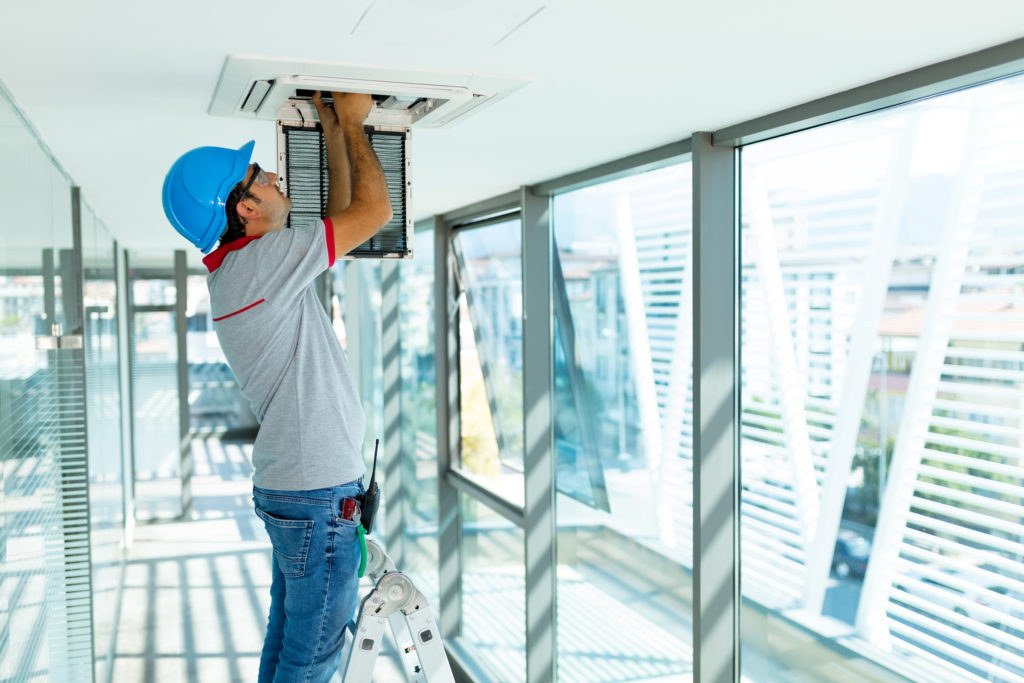 Man standing on ladder installing an air purification system in ceiling 